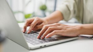 Persona escribiendo en ordenador portátil para blog de asesoría fiscal y laboral